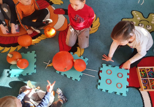 Dzieci wykonują działania matematyczne z wykorzystaniem dyni i darów Froebla